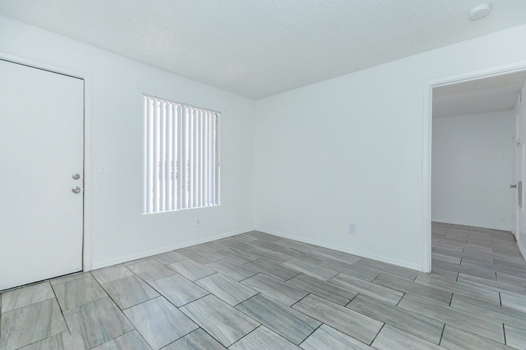 A room with a white door and a window with blinds.