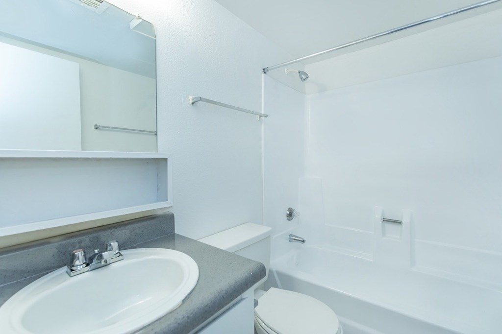 A white bathroom with a sink, toilet and bathtub.
