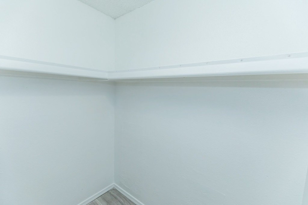 A corner of a room with white walls and a wooden floor.