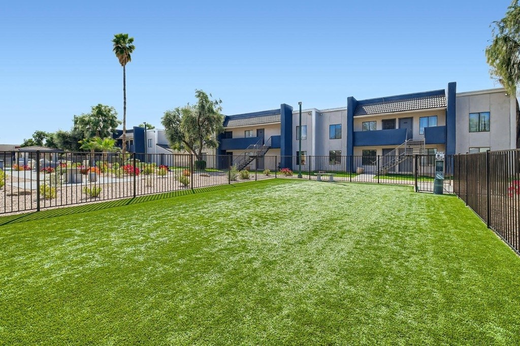 A large grassy area in front of a building with a fence.