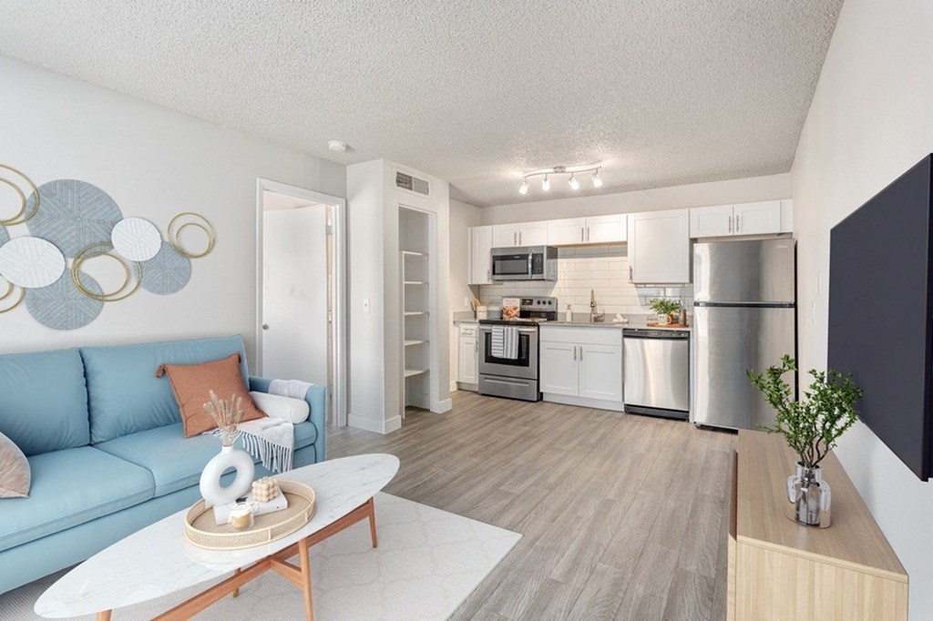 A modern kitchen with a blue couch and wooden flooring.