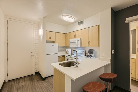 A kitchen with a white counter top and brown stools.