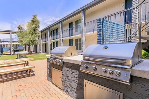 A BBQ grill is in front of a building with a balcony.