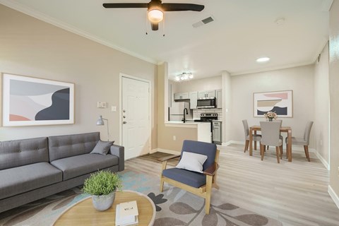 A living room with a grey couch, a blue chair, and a coffee table with a plant on it.