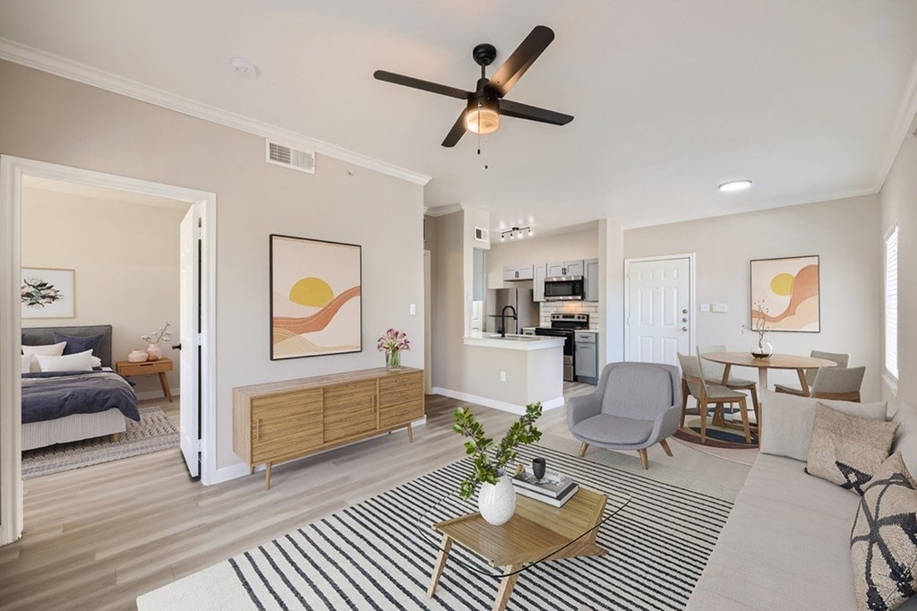A living room with a ceiling fan and a striped rug on the floor.