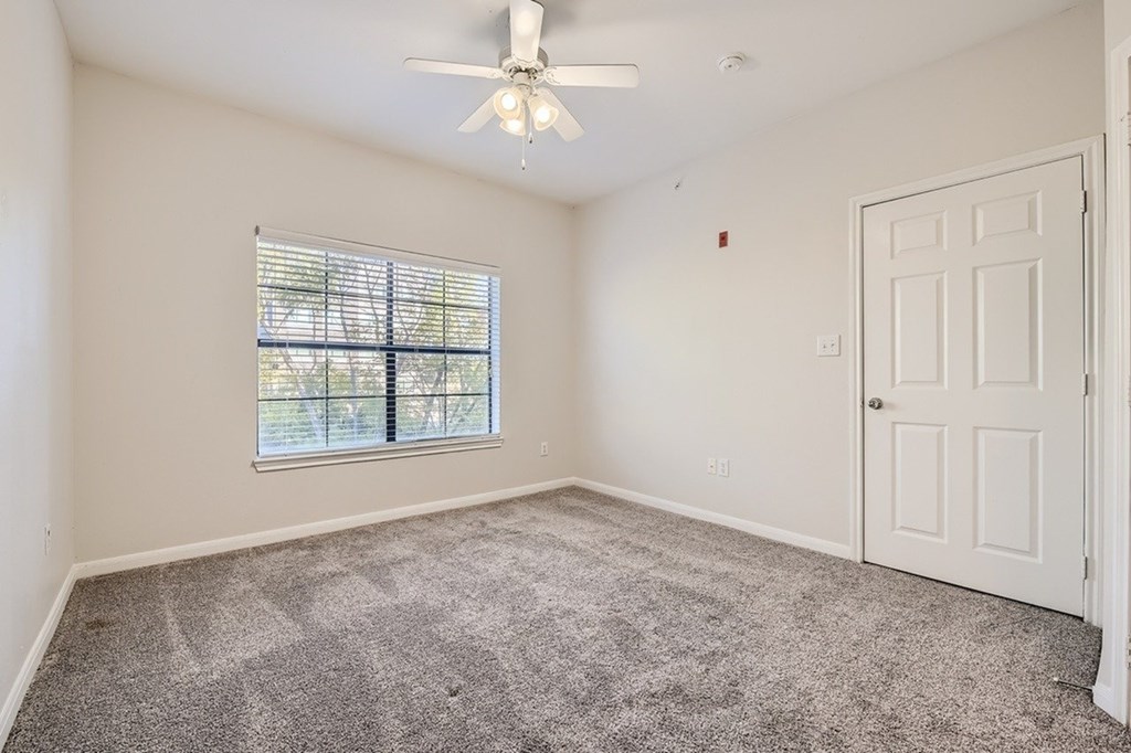 A room with a ceiling fan and a window with blinds.