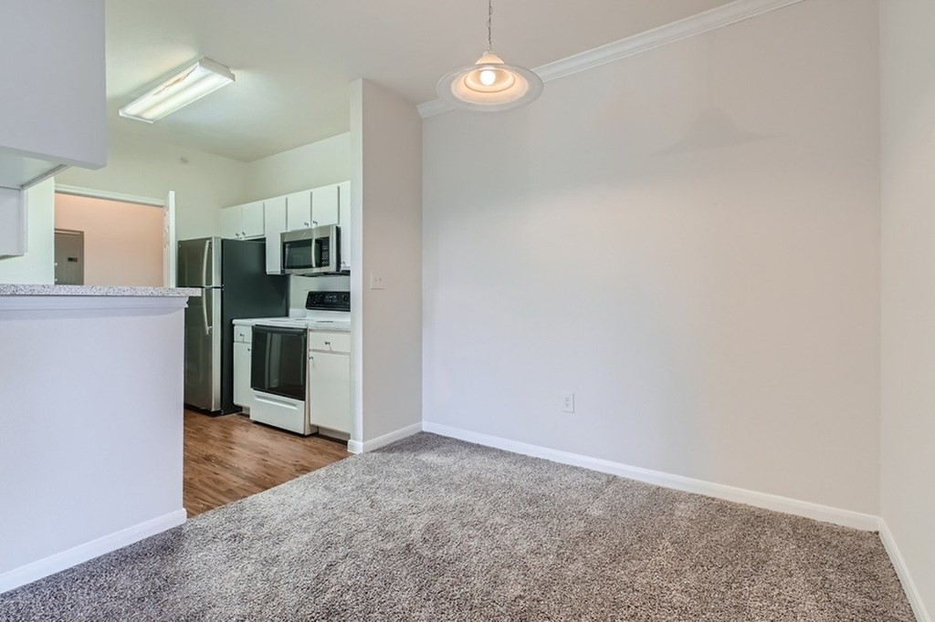 A kitchen with white cabinets and a fridge.