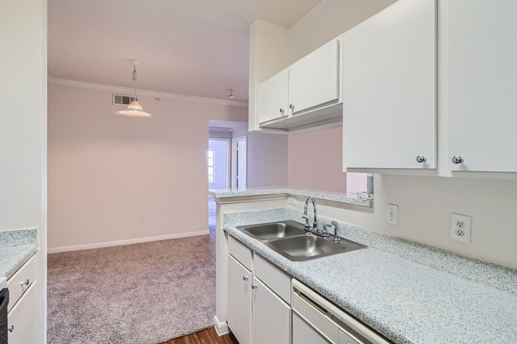 A kitchen with white cabinets and a granite countertop.