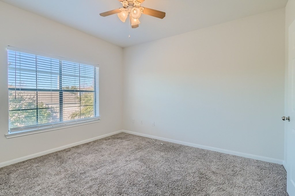 A room with a ceiling fan and a window with blinds.