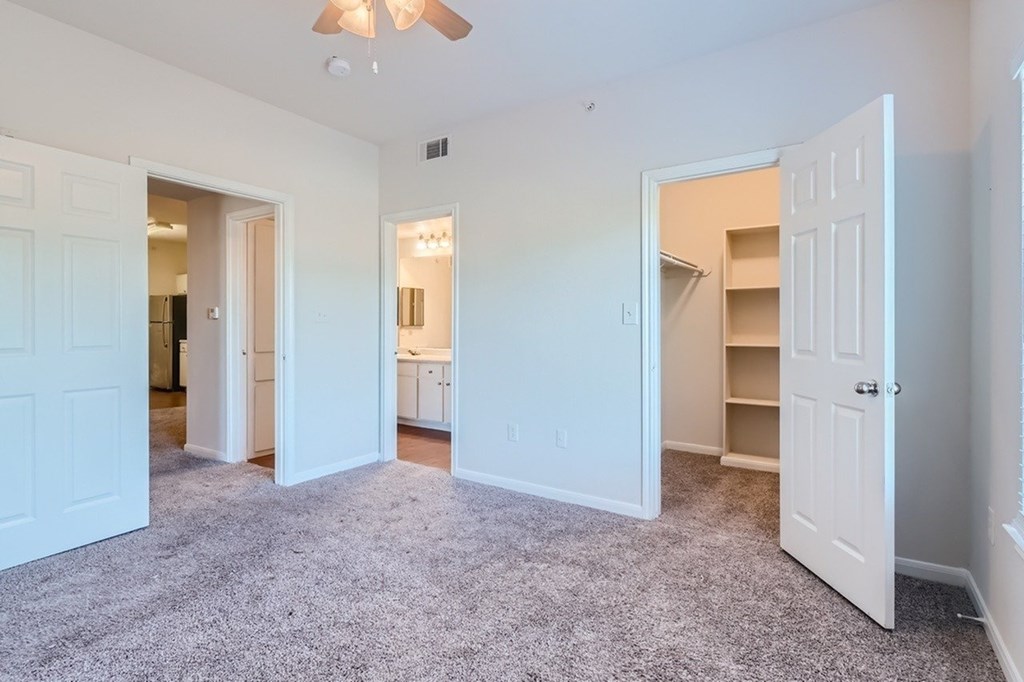A spacious room with white walls and a ceiling fan.