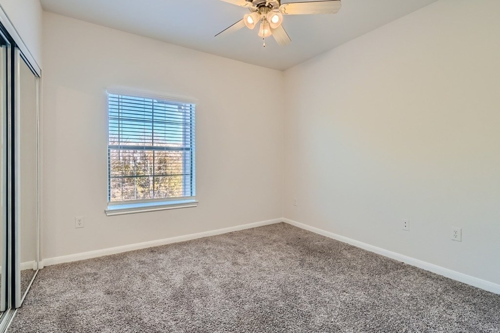 A room with a ceiling fan and a window with blinds.