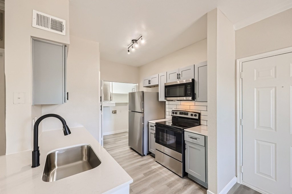 A kitchen with a stainless steel sink and refrigerator.