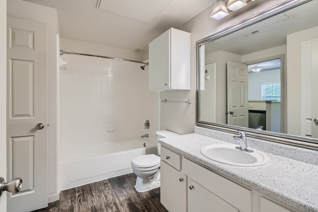 A white bathroom with a toilet, sink, and mirror.