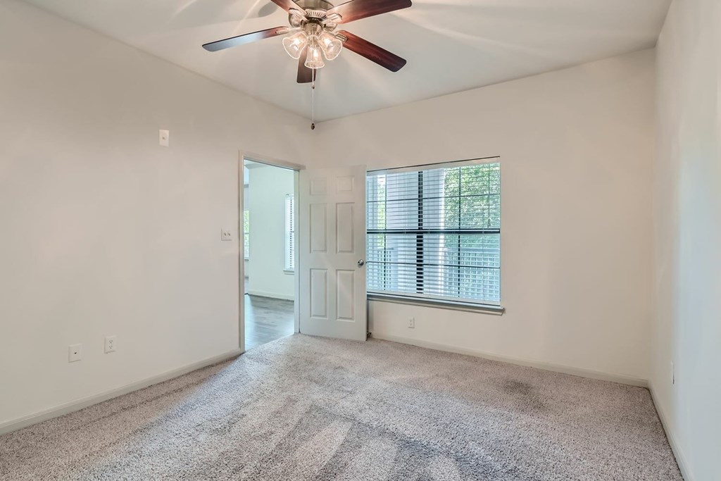 A room with a ceiling fan and a window with blinds.