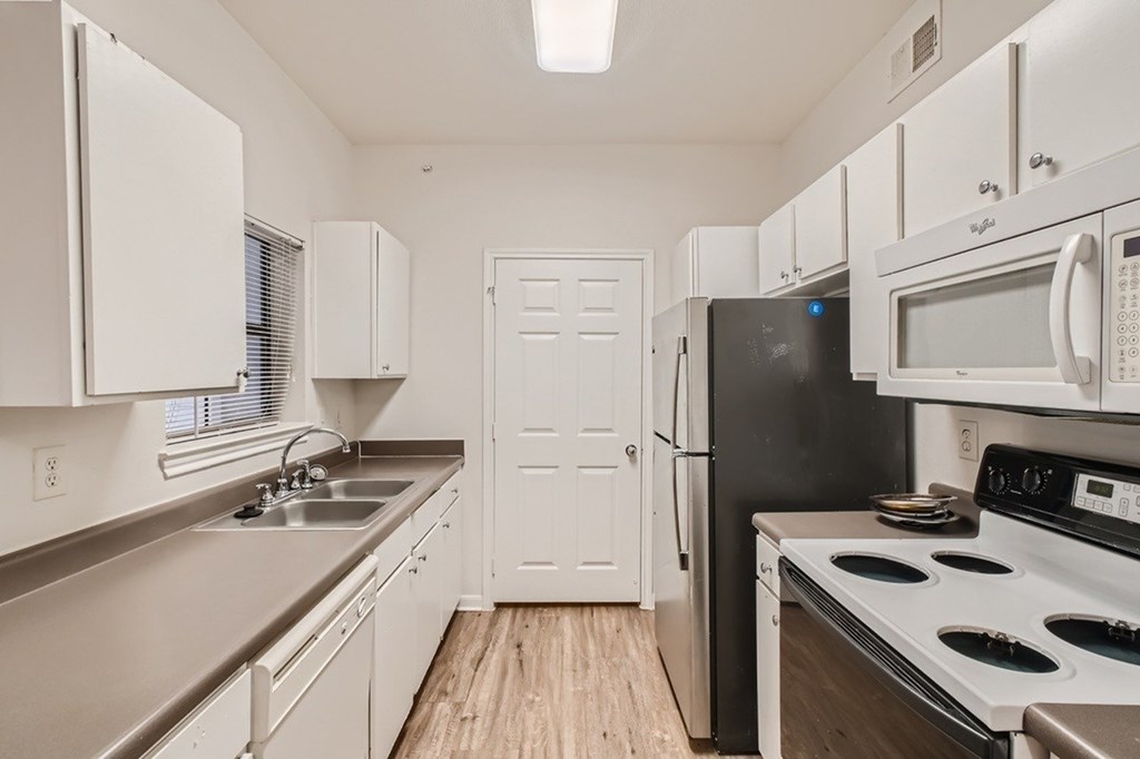 A kitchen with white cabinets and a black refrigerator.