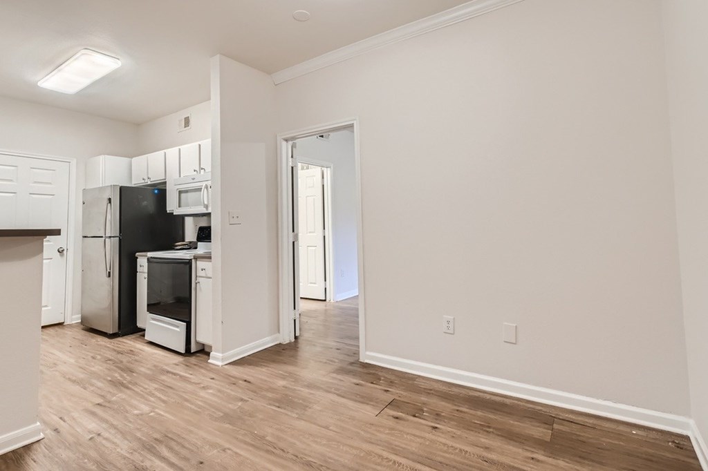 A kitchen with white cabinets and a black fridge.