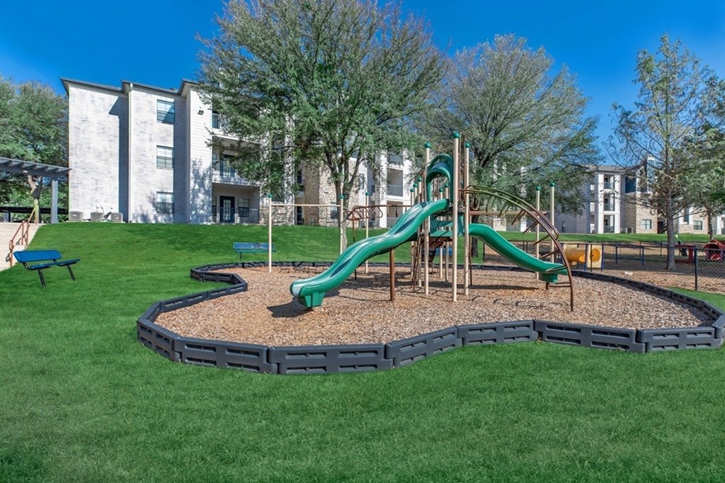 A playground with a green slide and a blue bench.