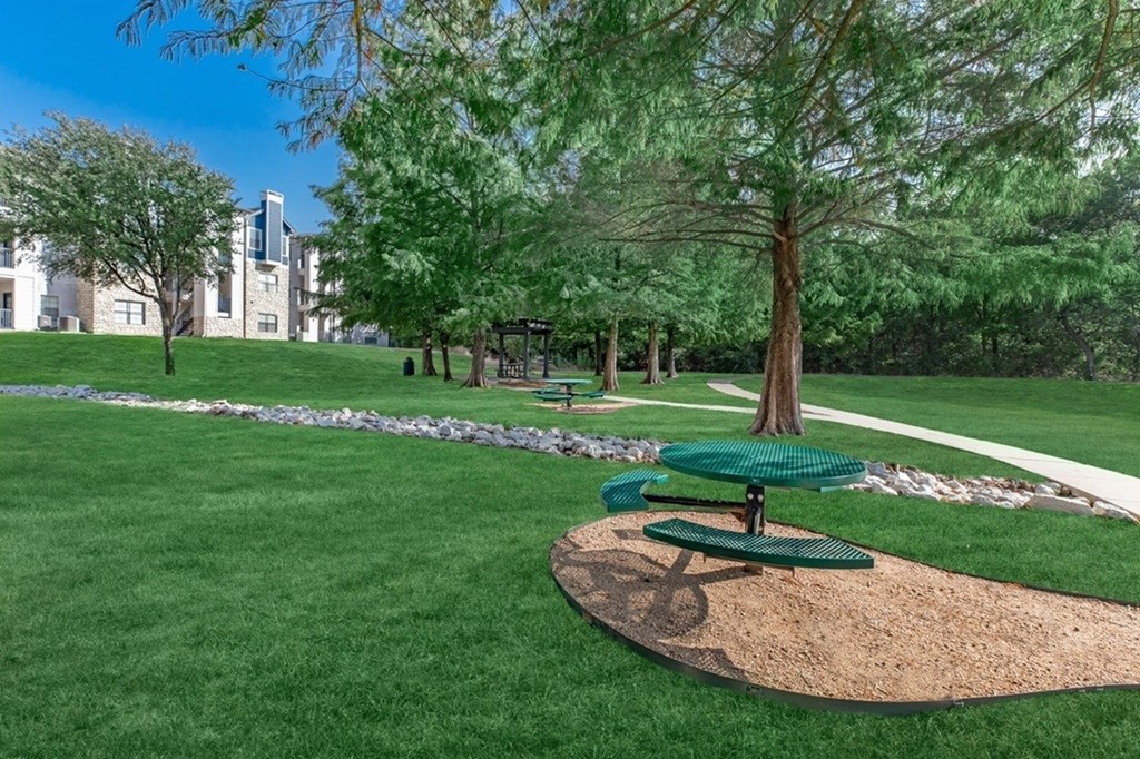 A park with a picnic table and a tree in the foreground.