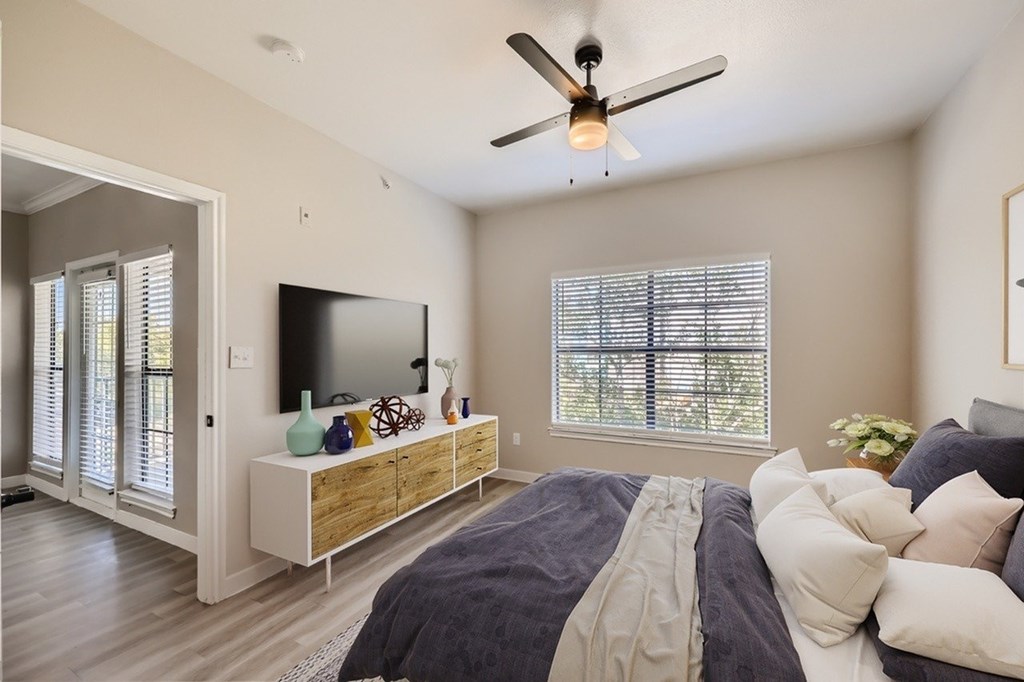 A bedroom with a bed, a television, and a window with blinds.