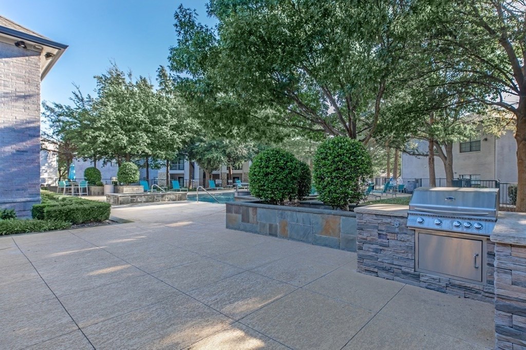 A patio with a stone wall and a grill.