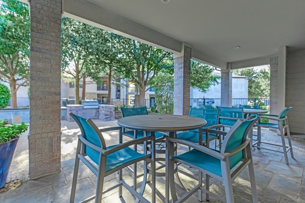 A patio with a table and chairs under a roof.