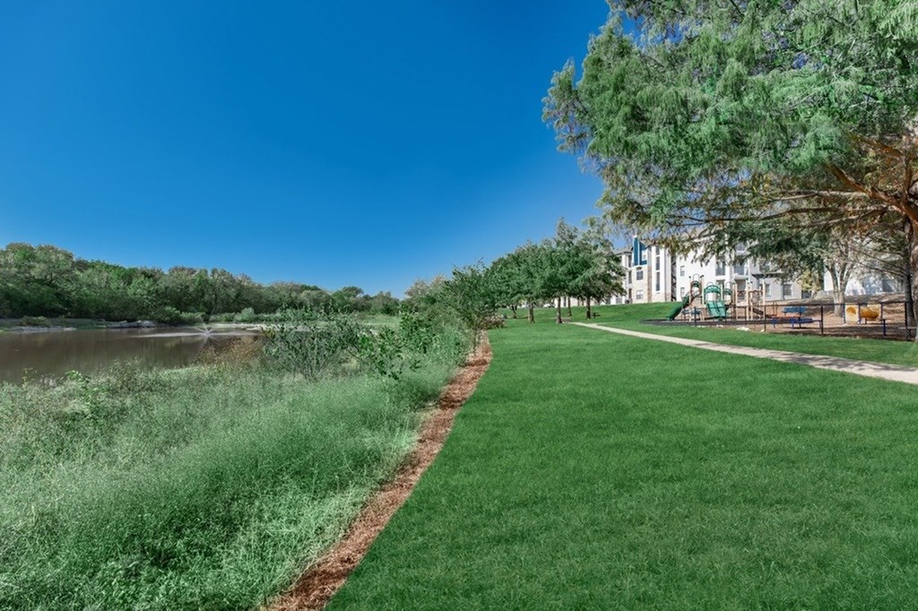 A park with a walking path next to a river.
