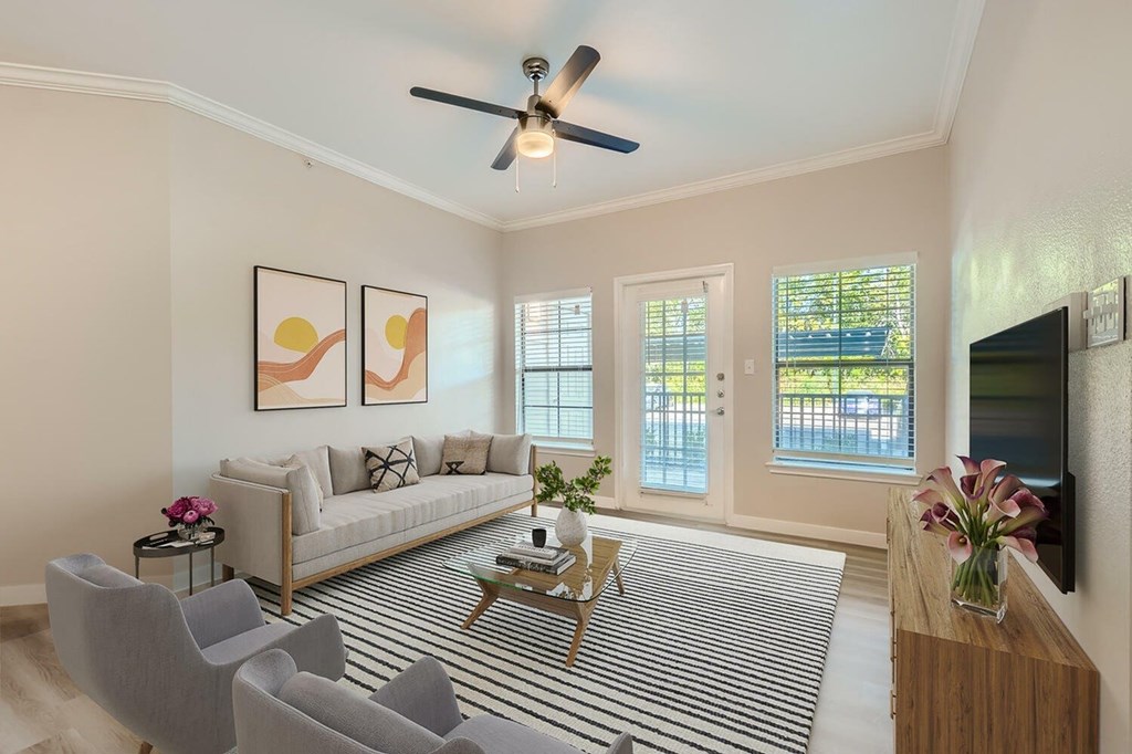 A living room with a striped rug, a sofa, a coffee table, and a ceiling fan.