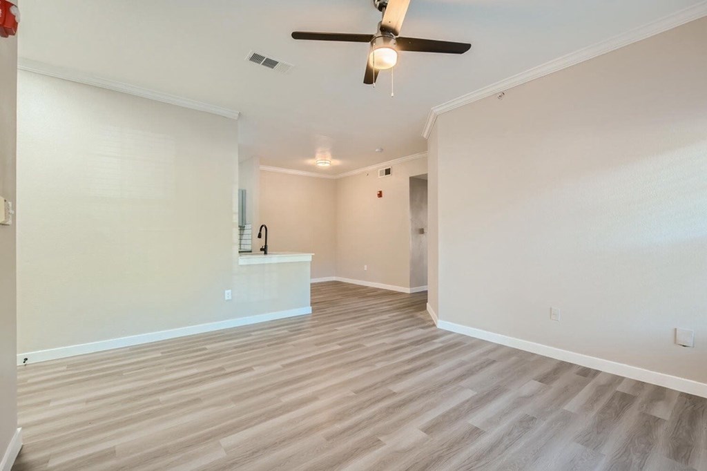 A room with a ceiling fan and light fixture, and a wooden floor.