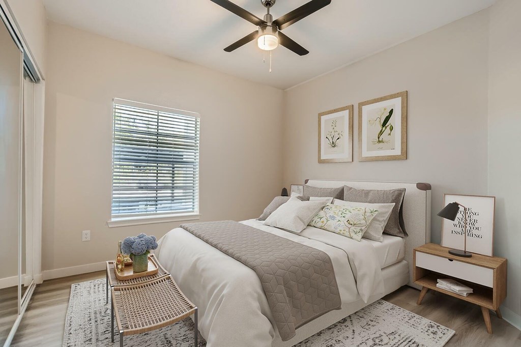 A bedroom with a bed, nightstand, and two pictures on the wall.