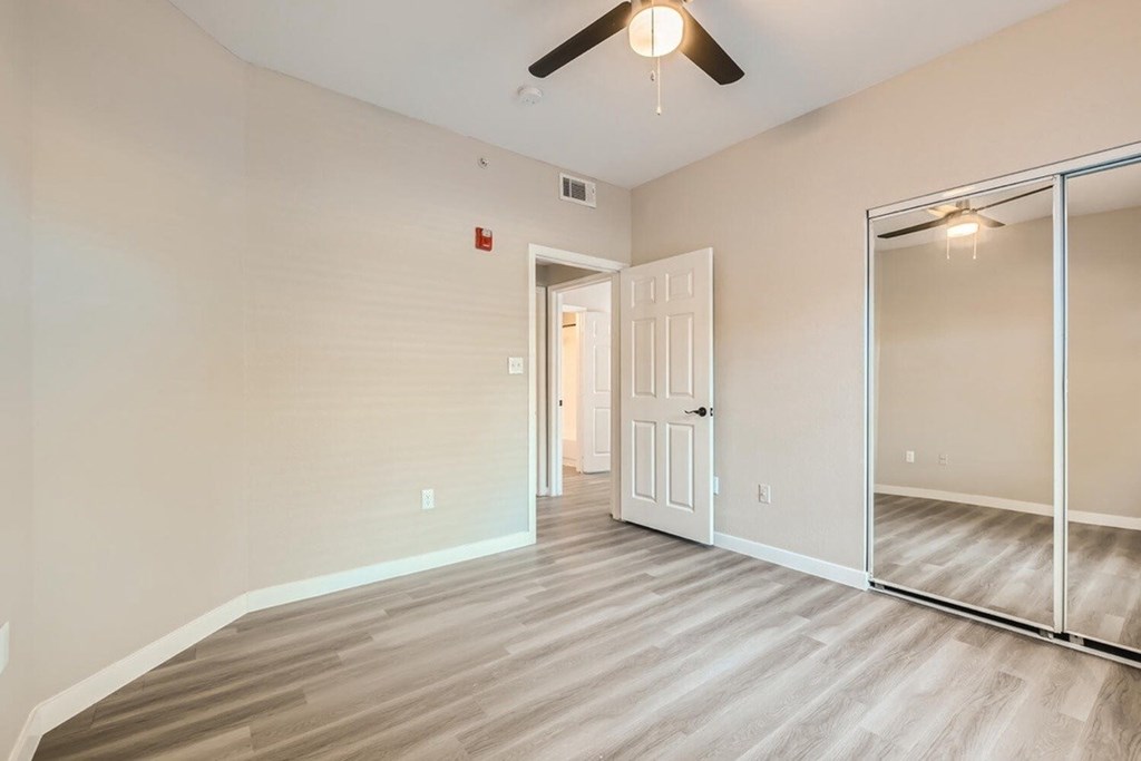 A room with a ceiling fan and a door leading to another room.