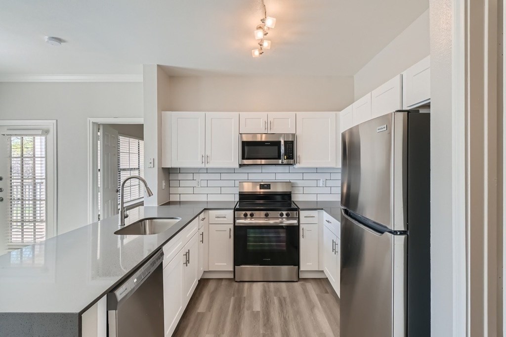 A modern kitchen with stainless steel appliances and white cabinets.