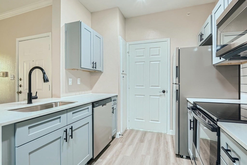 A kitchen with a sink, cabinets, and a refrigerator.