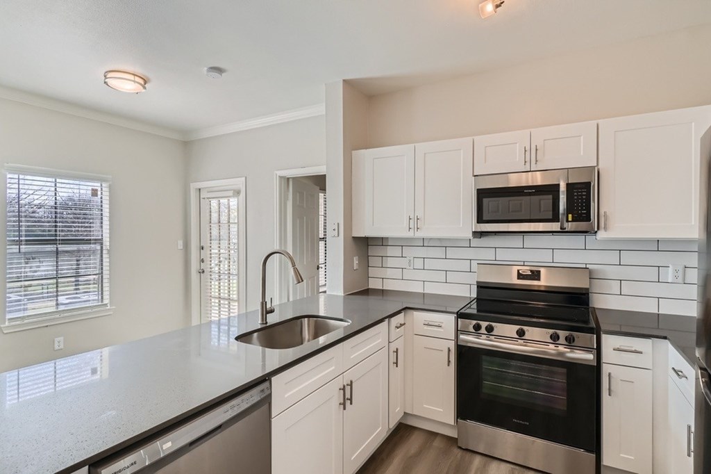 A kitchen with white cabinets and black countertops.