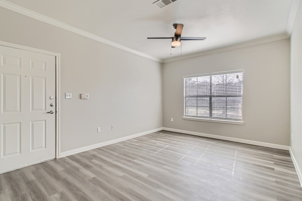 A room with a white door, a window with blinds, and a ceiling fan.