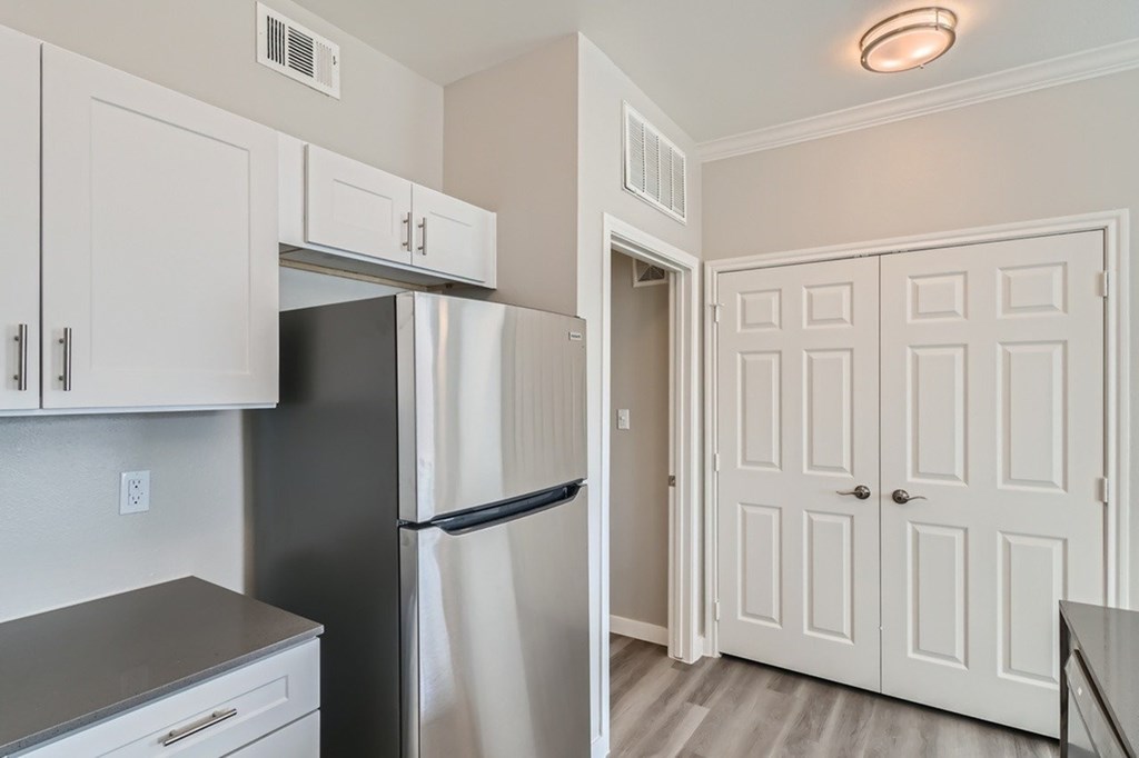 A kitchen with a black refrigerator and white cabinets.