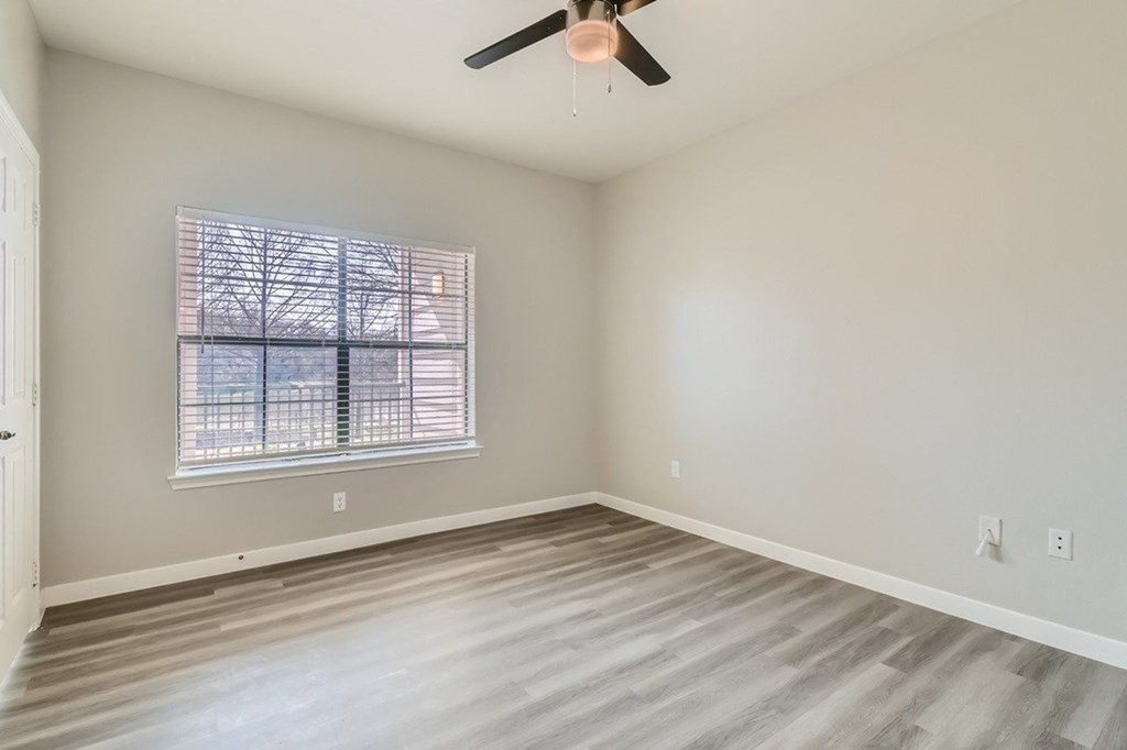 A room with a ceiling fan and a window with blinds.