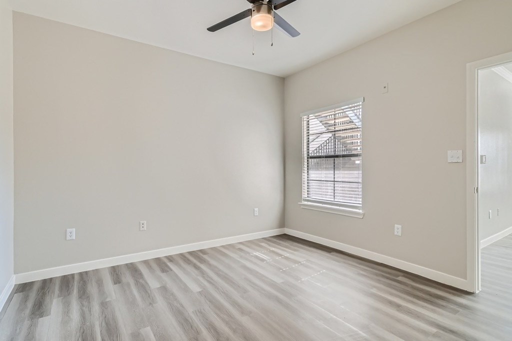 A room with a ceiling fan and a window with blinds.