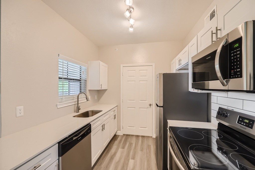 A kitchen with a black stove top oven and a black microwave above it.