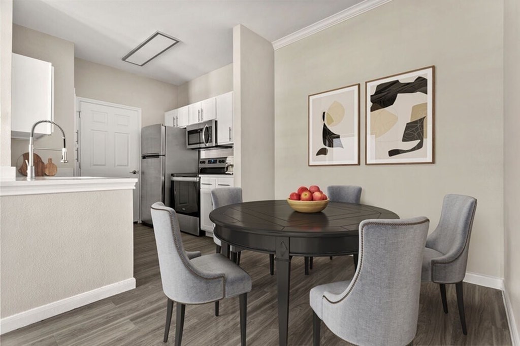 A modern dining room with a round table and grey chairs.