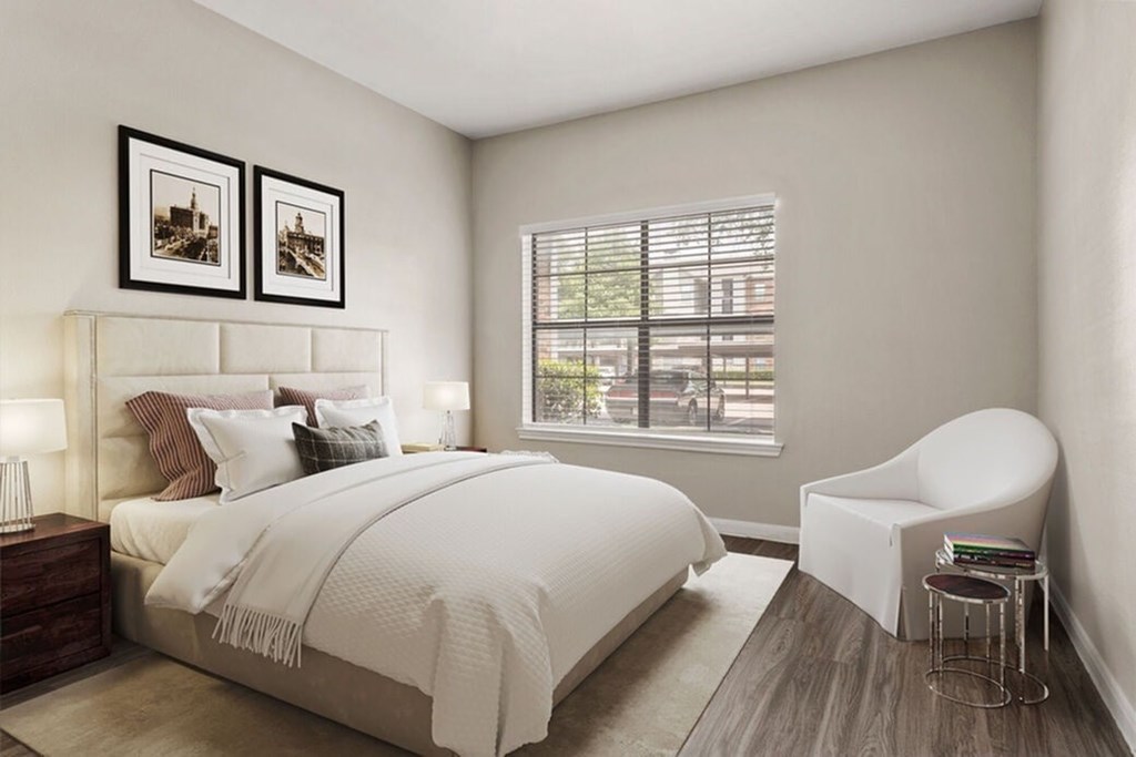 A bedroom with a large bed and a chair.