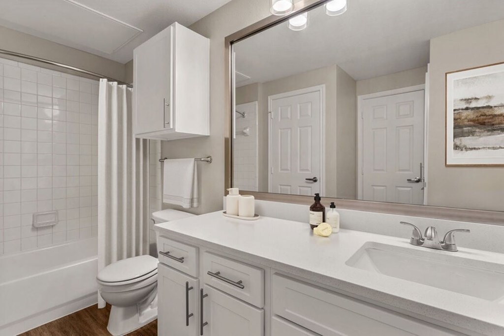 A white bathroom with a toilet, sink, and mirror.