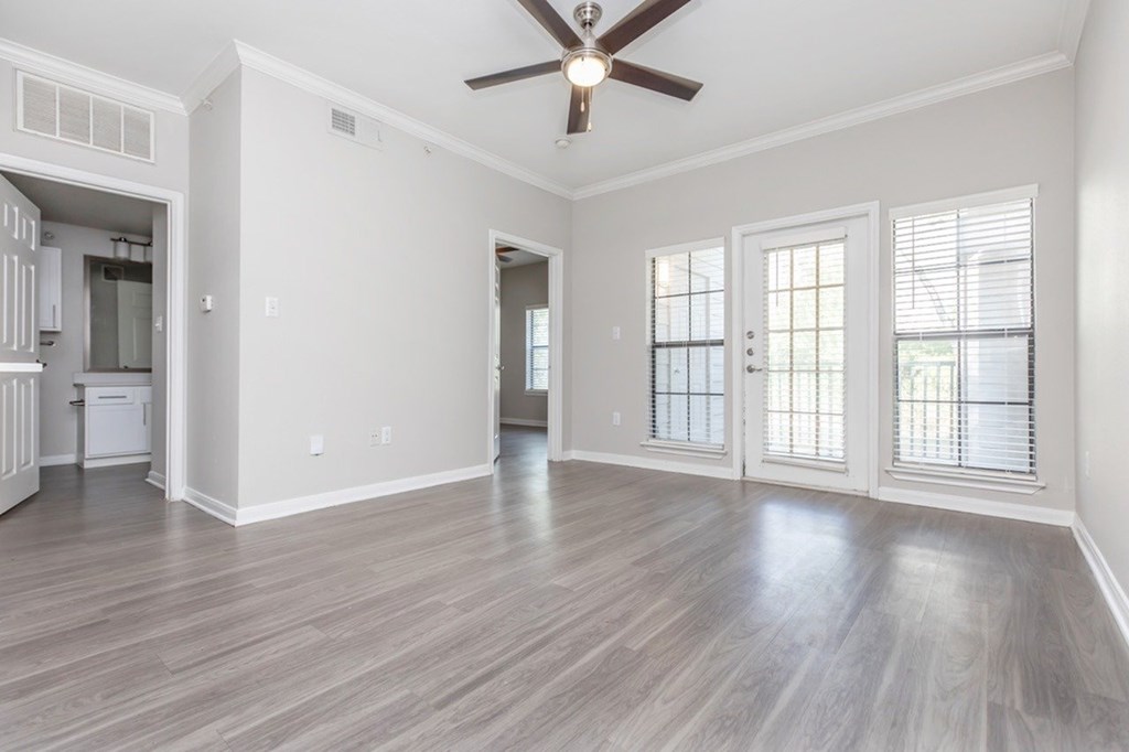 A spacious room with a ceiling fan and hardwood flooring.