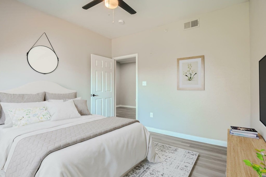 A bedroom with a bed, a ceiling fan, and a door.