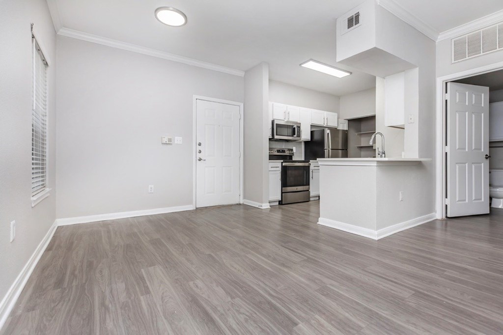 A kitchen with a white countertop and wooden flooring.