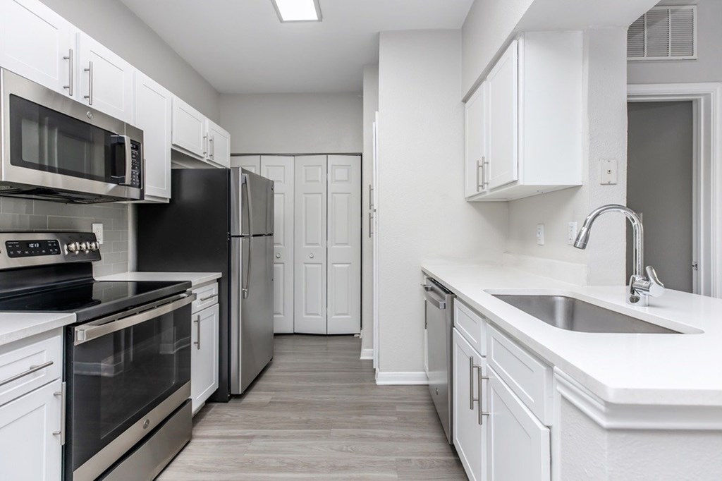 A kitchen with white cabinets and black appliances.