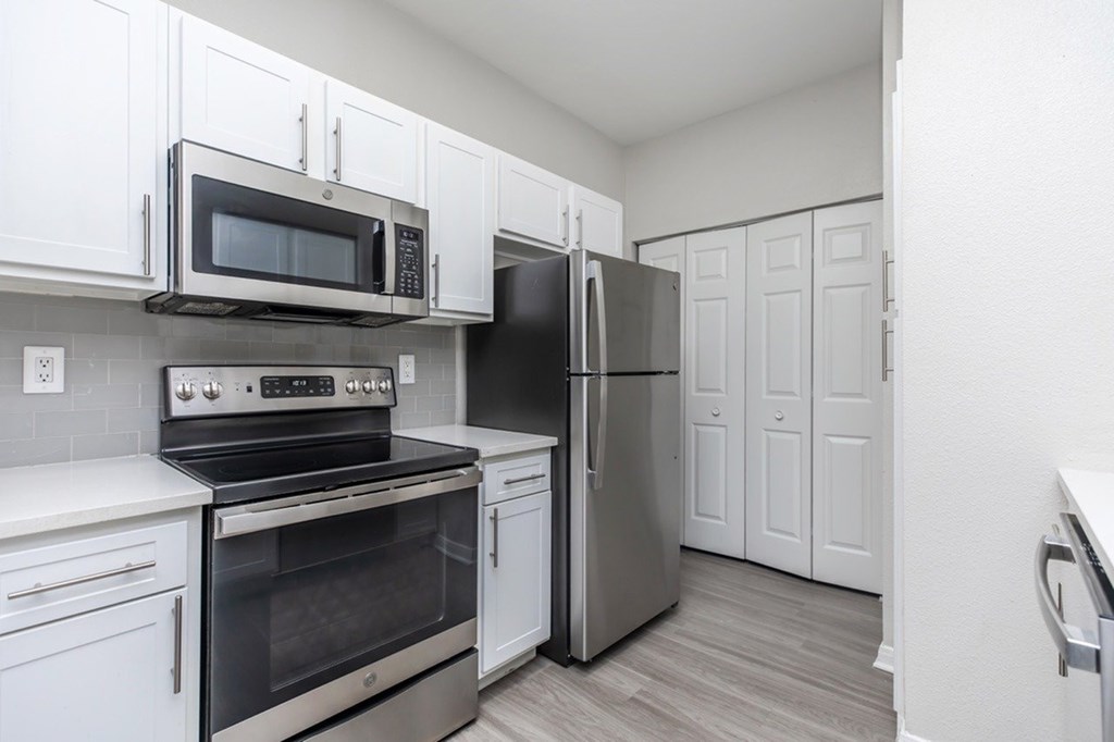 A kitchen with white cabinets and stainless steel appliances.