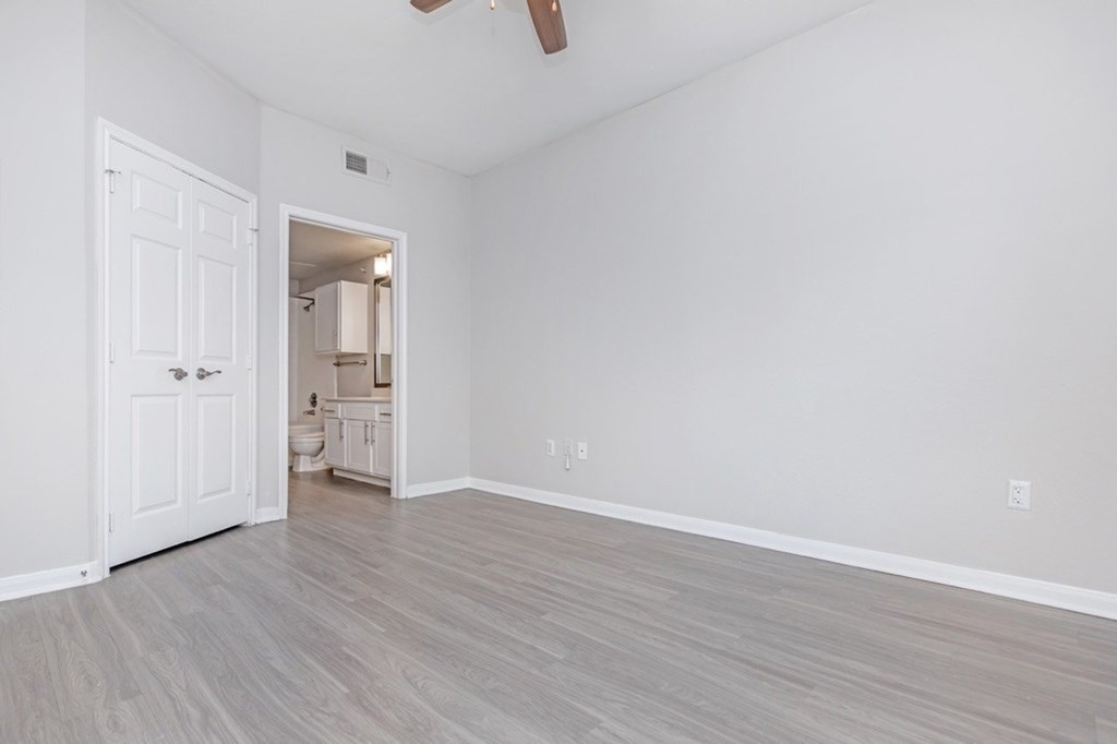 A room with a white door and a ceiling fan.
