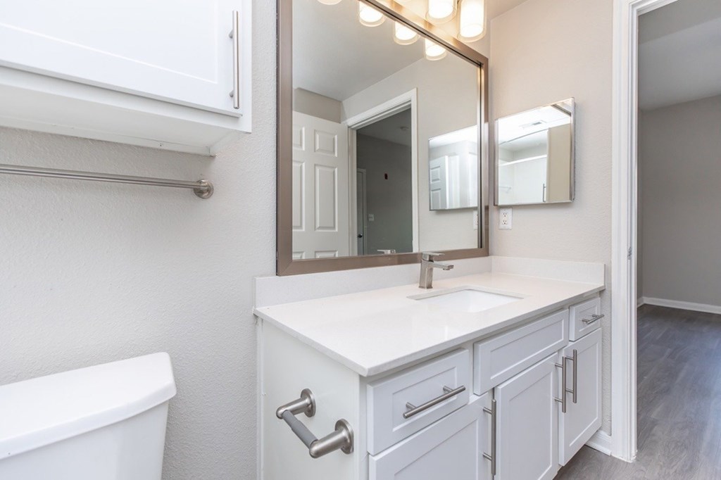 A white bathroom with a tub, sink, and mirror.