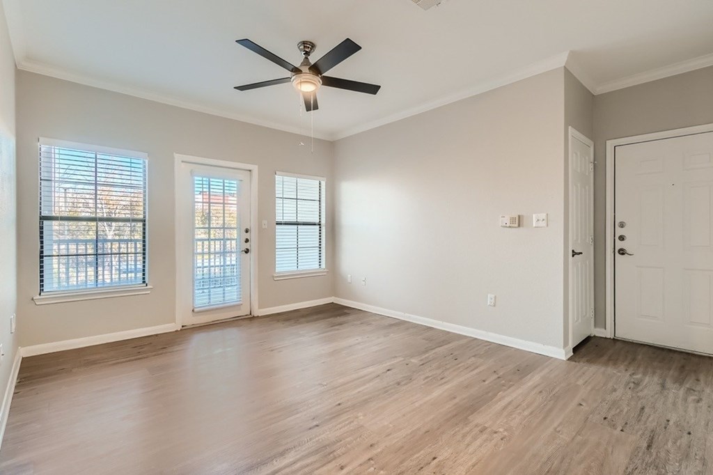 A room with a ceiling fan and wooden flooring.