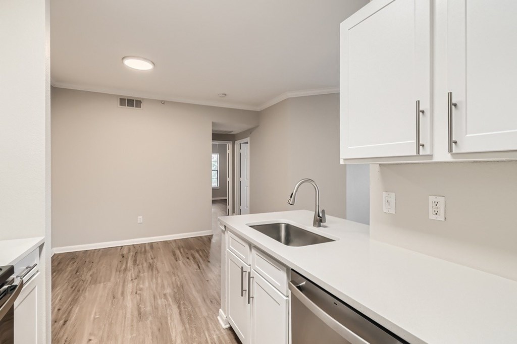 A kitchen with white cabinets and a stainless steel sink.